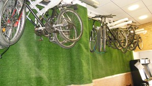 Fahrräder an einer Wand in einem Raum mit grünem Teppich und Holzelementen.