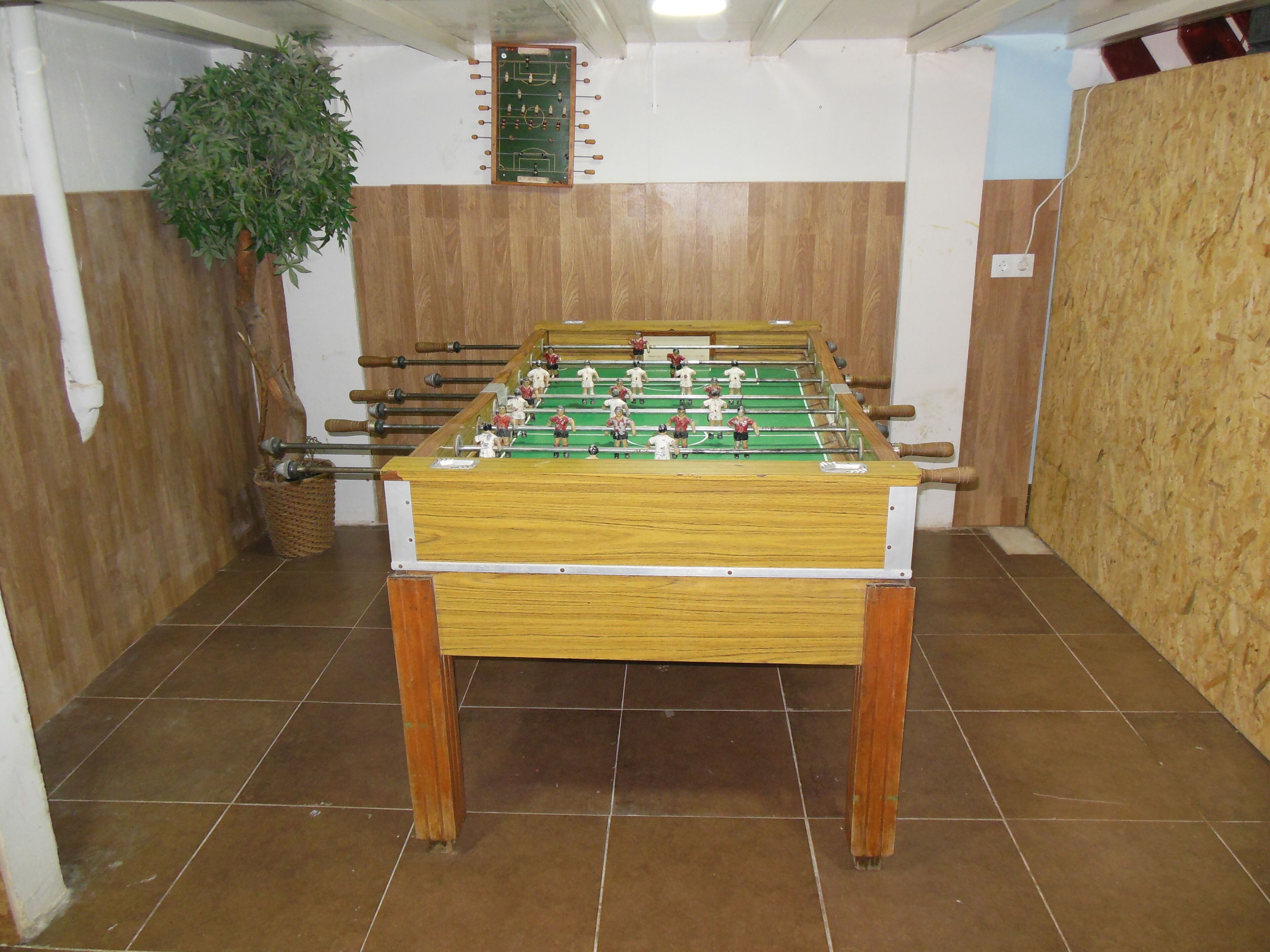 A foosball table in a room with wooden walls and tiled flooring.