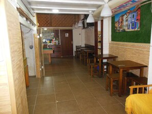 Un restaurant amb taules i caires de fusta, un sòl de rajola i un mural a la paret.