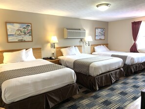 A hotel room with three beds, a ceiling fan, wall-mounted air conditioning, and artwork. - Sandusky Inn (Sandusky)