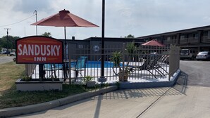 Señal de Sandusky Inn, con un área de piscina visible al fondo.