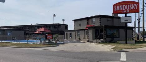 Un hôtel à Sandusky, reconnaissable à son grand panneau rouge, à sa piscine entourée d’une clôture et à son parking.