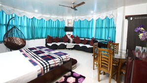 A modern living room with a sofa, a hanging chair, a dining table with chairs, and a ceiling fan. - Vrinda Palace (Mathura)
