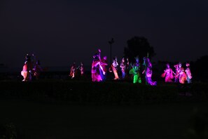 A nighttime outdoor scene with illuminated statues of figures in various poses. - Vrinda Palace (Mathura)