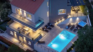 Uma casa moderna de dois andares com piscina, área de estar externa e ofurô.
