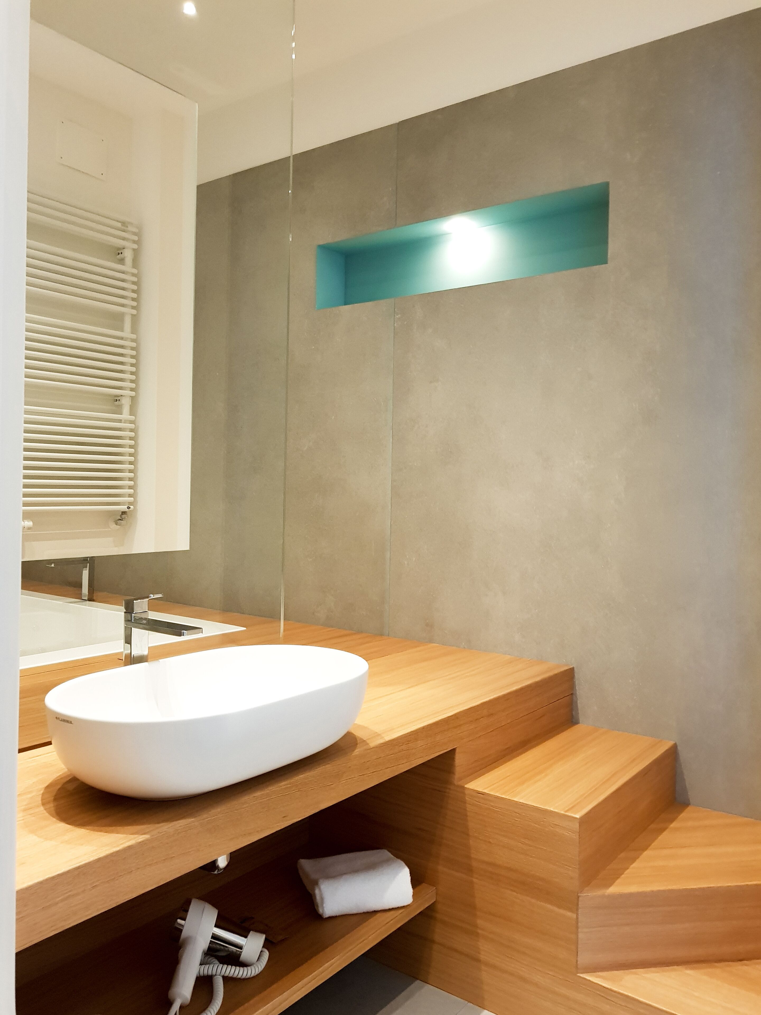 Une salle de bain moderne avec un grand lavabo blanc, un meuble-lavabo en bois et une zone de douche intégrée.