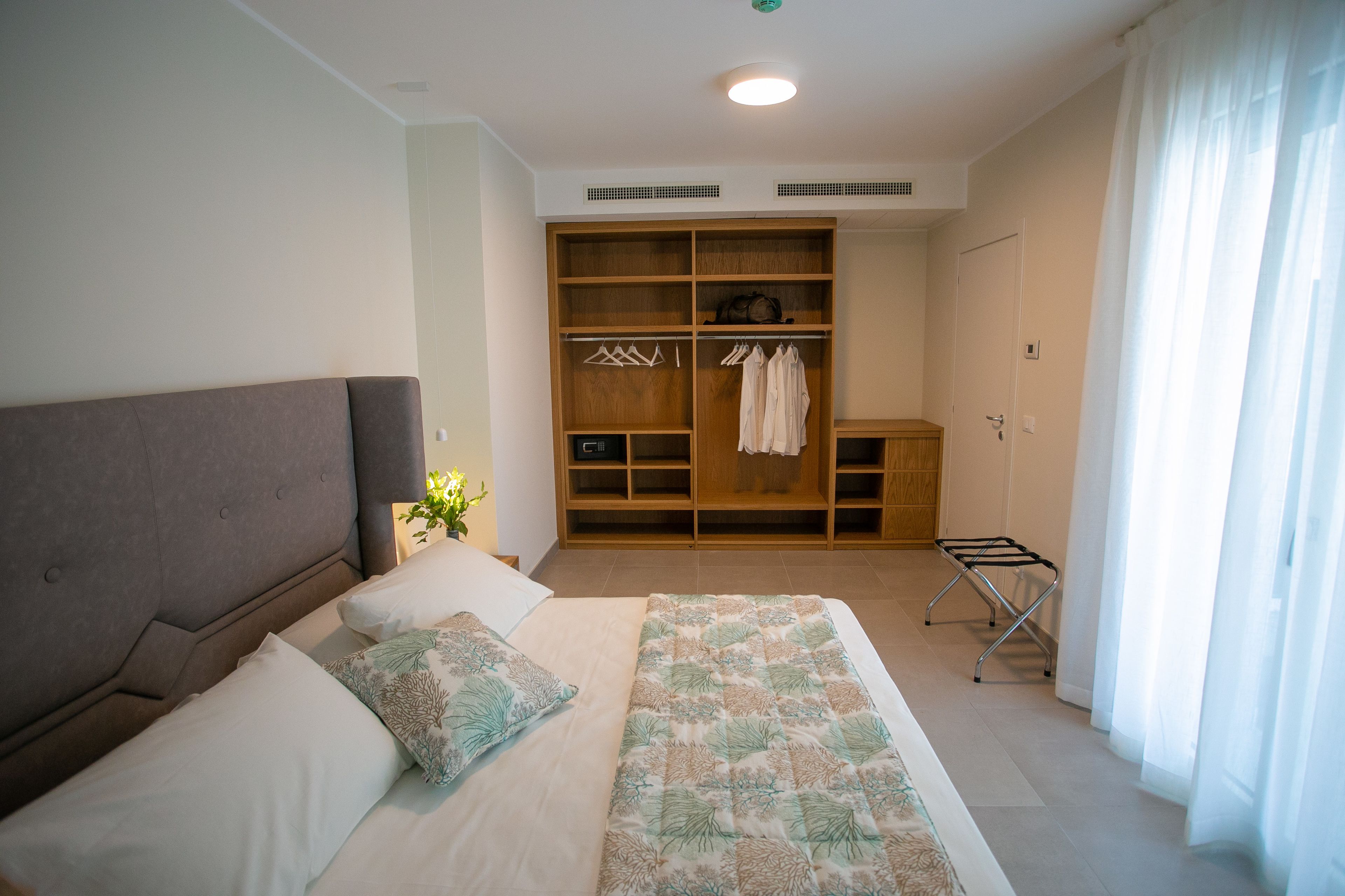 A bedroom with a bed, a wardrobe, and a drying rack.