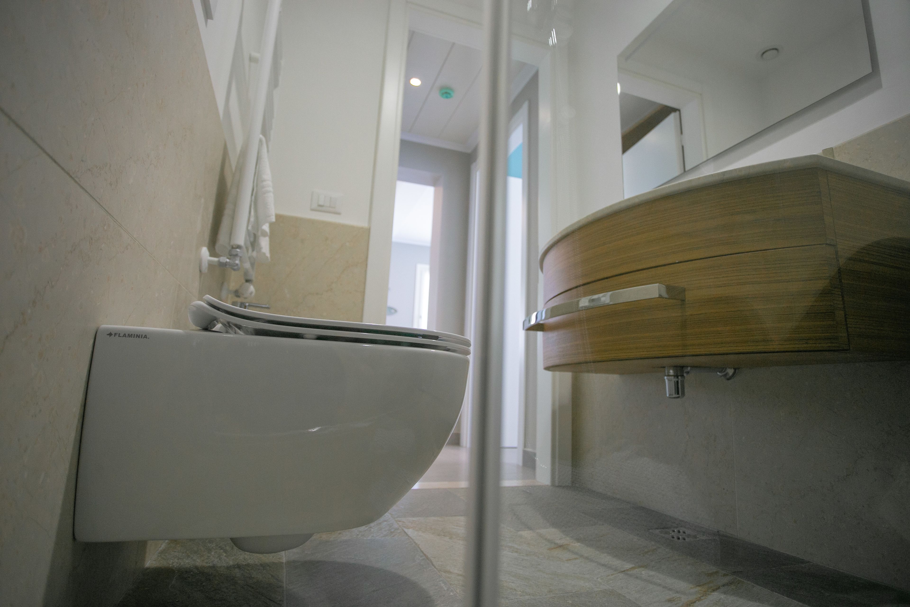 A modern bathroom with a white toilet, a wooden vanity, and a mirror.