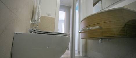 Un bagno moderno con il water bianco, un mobile lavabo in legno e uno specchio.