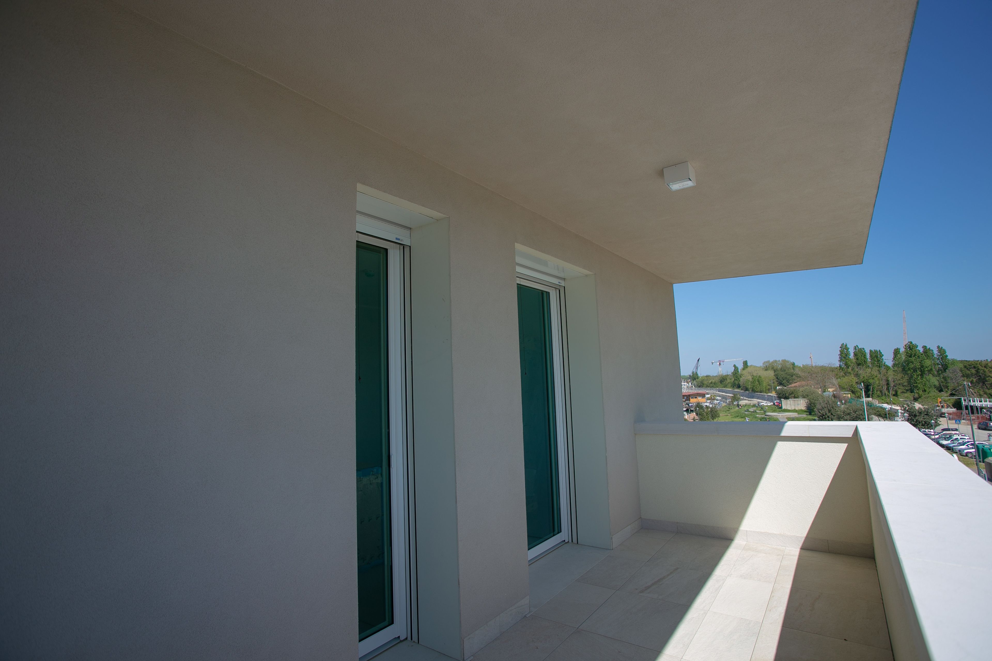 A balcony with a view of a town and construction cranes in the distance.