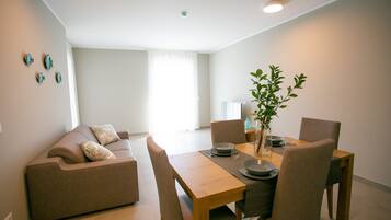 Un salon moderne avec un canapé, une table à manger, des chaises et une plante.