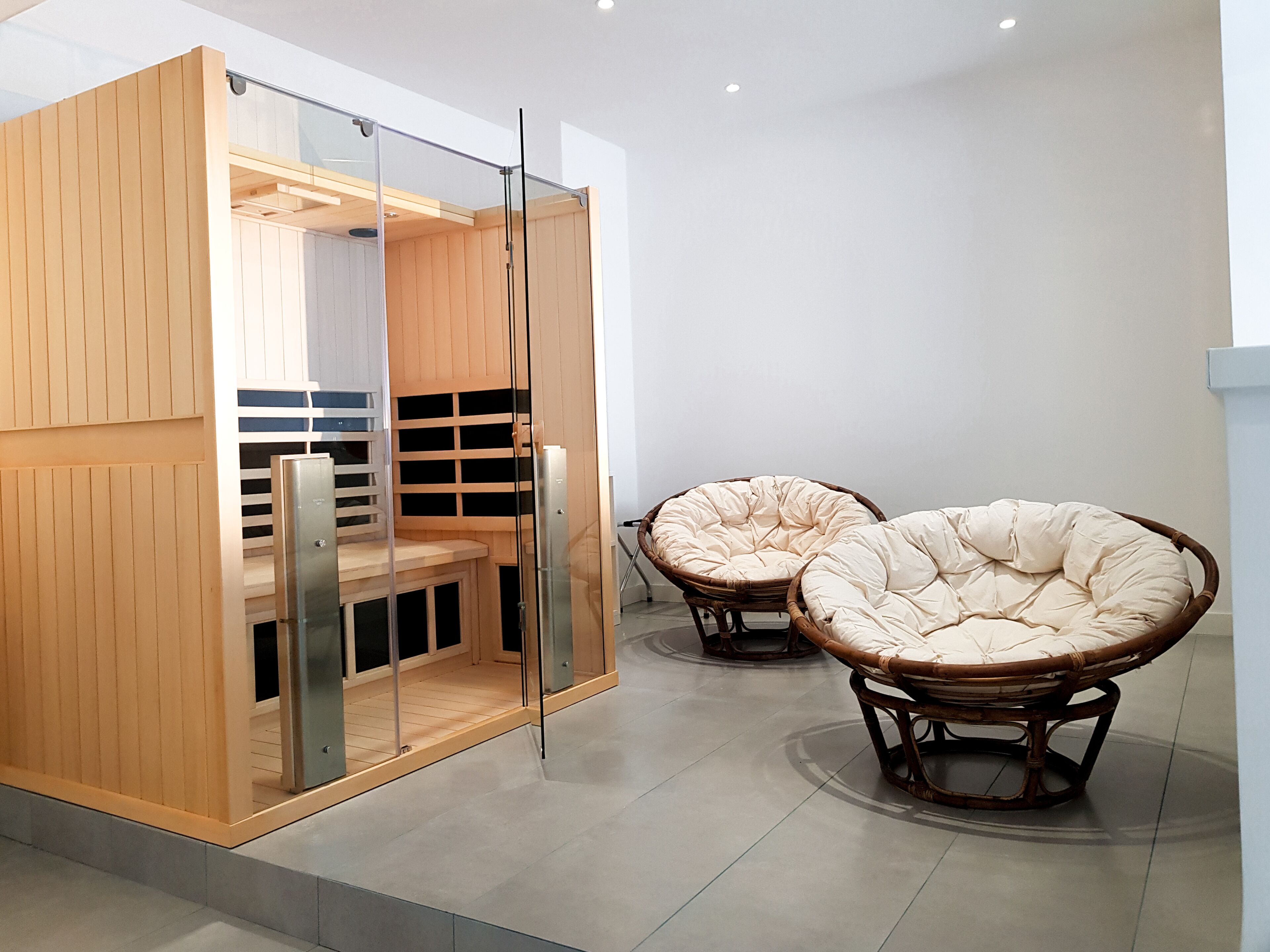 A modern interior with a wooden storage unit, glass doors, and two wicker chairs.