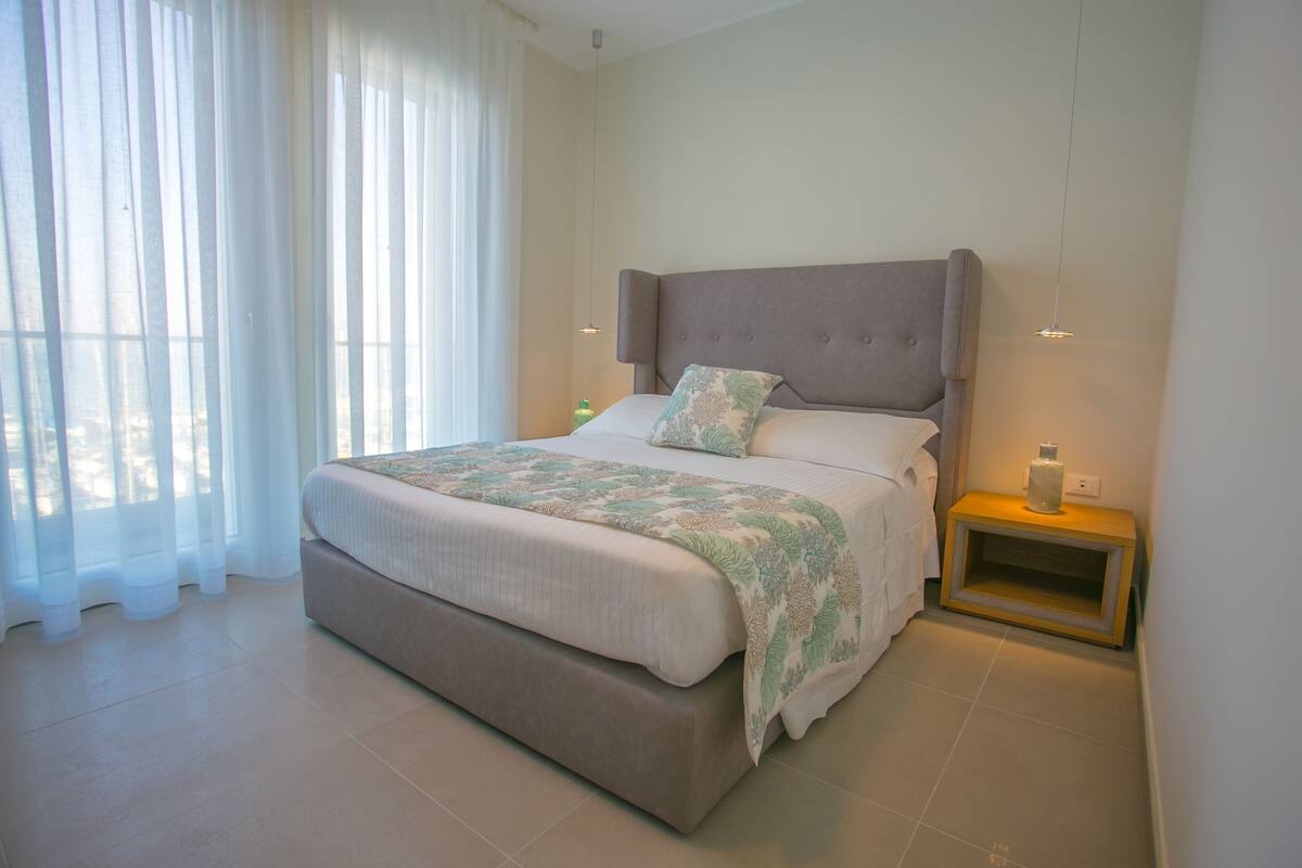 Une chambre moderne avec un grand lit, une table de chevet et une commode.
