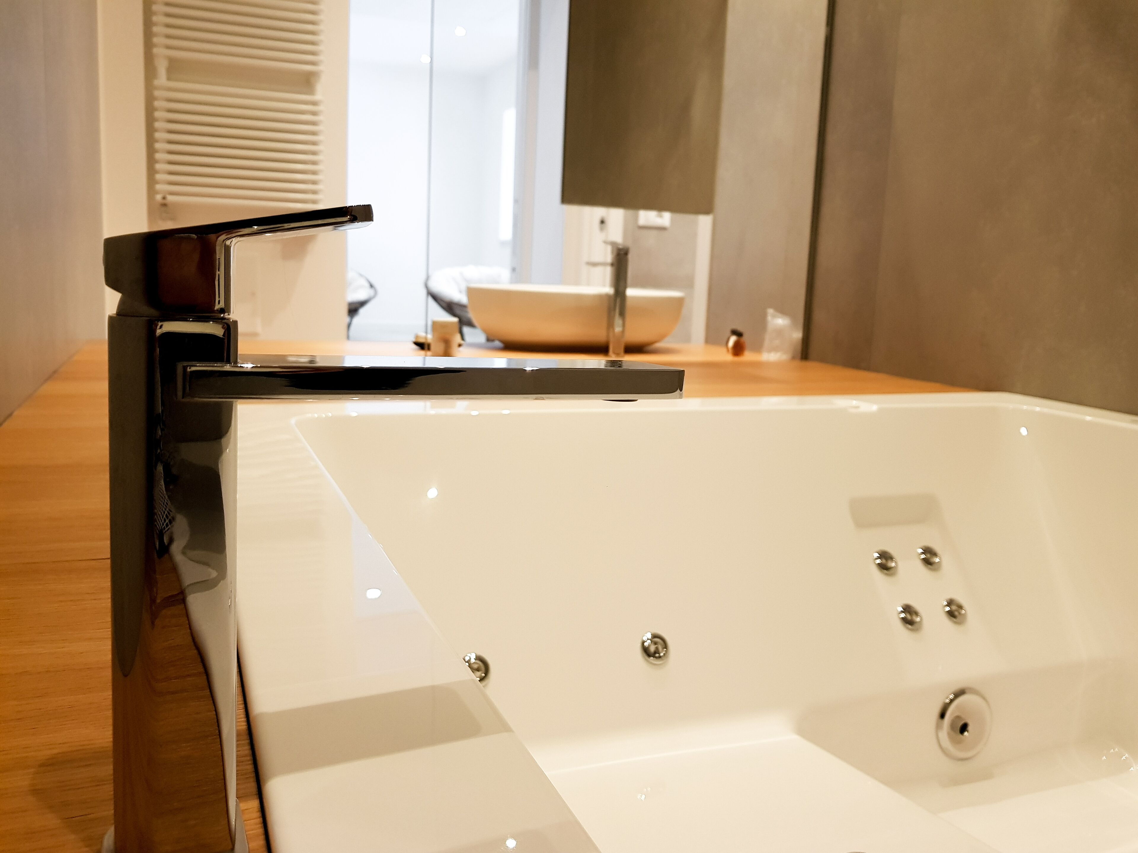 Un baño moderno con una bañera blanca grande, un grifo negro elegante y una encimera de madera.