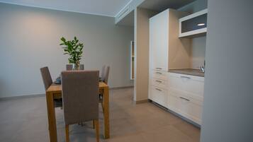 A modern kitchen with white cabinets, a dining table with chairs, and a potted plant.