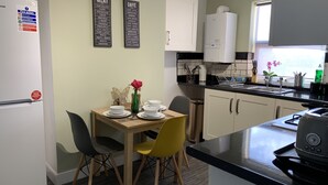 A modern kitchen with a dining area, featuring a refrigerator, a coffee machine, and a sink. - Buccleuch Apartment (Kettering)
