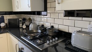 A modern kitchen with white cabinets, black countertops, and a gas stove. - Buccleuch Apartment (Kettering)