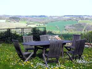 A table and chairs set on a grassy hill with a view of a valley. - Les Chimeres (Puylaroque)