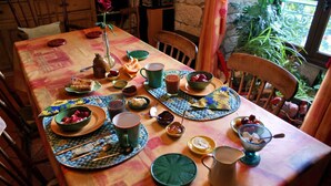 Una mesa de comedor preparada con platos, tazones, tazas y una jarra, rodeada de sillas.