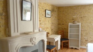 Una habitación con chimenea, un escritorio, una silla y una estantería.