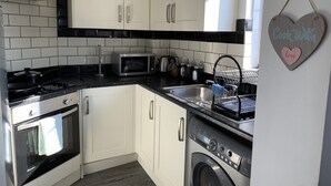 A modern kitchen with white cabinets, a stainless steel range, a microwave, and a dishwasher. - Eskdaill Place Apartment (Kettering)