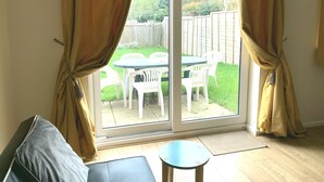 A room with a sliding glass door leading to a patio with a table and chairs. - Cosy Corner House (Kettering)