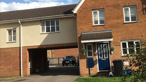 A two-story residential building with a garage entrance, a blue front door, and a brick facade. - Cosy Corner House (Kettering)