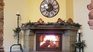 A stone fireplace with a clock above it, adorned with festive decorations. - Hotel Bor (Lhota)
