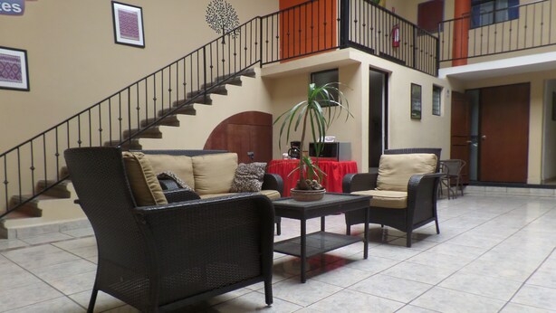 Un vestíbulo con mobiliario de mimbre, una escalera y un mantel rojo.