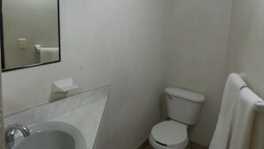 Un baño pequeño y blanco con inodoro, lavamanos y espejo.