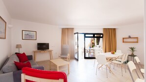 A modern living room with a sofa, TV, and dining area. - Club Oceano (Tías)