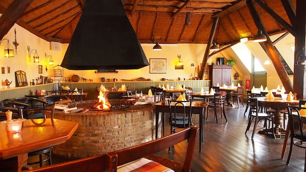 A restaurant with a brick fireplace, wooden tables, and chairs.