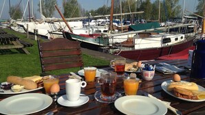A table set with breakfast items and a view of boats in the background.