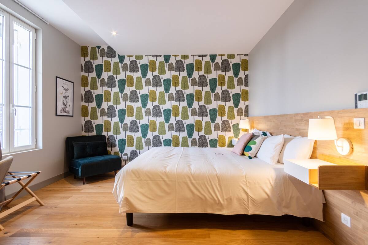 A bedroom with a bed, bedside tables, a desk, and a chair.