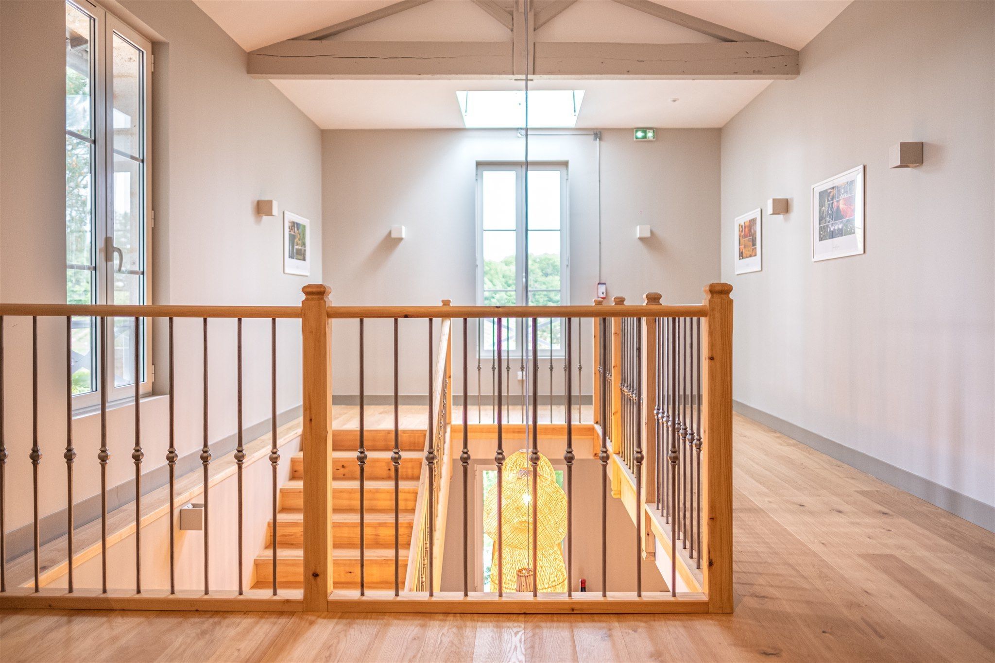 A spacious interior with a wooden staircase, large windows, and a high ceiling.