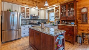 A kitchen with wooden cabinets, stainless steel appliances, granite countertops, and pendant lighting. - Cardinal's Nest- Along Cranberry Creek, great for tubing, kayaking (Elk Park)