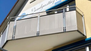 Un edificio con balcón que presenta barandillas de metal perforado y un cartel que dice "Landgasthof Cell".