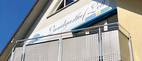 A building with a balcony featuring perforated metal railings and a sign that reads "Landgasthof Cell".