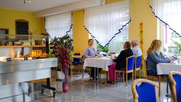 Comedor con mesas y sillas, un mostrador de buffet y un menú en la pizarra.