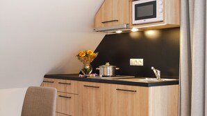 Una kitchenette con armarios de madera, un microondas, un fregadero y un florero con flores.