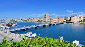 Un puerto deportivo con barcos amarrados, un puente peatonal y edificios al fondo.
