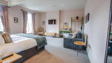 Una habitación de hotel con cama, escritorio, silla, mesita y sofá.