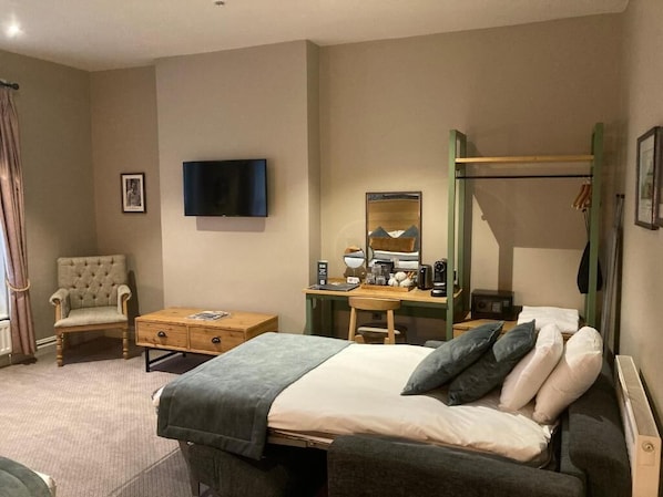 A hotel room with a bed, a desk, a chair, a television, a mirror, and a bunk bed. - The Black Hat (Ilkley)