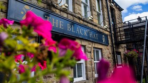 Un edificio de piedra con un cartel que dice 'THE BLACK HAT'.
