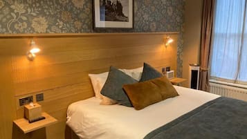 A neatly made bed with pillows, a bedside lamp, and a framed picture on the wall.