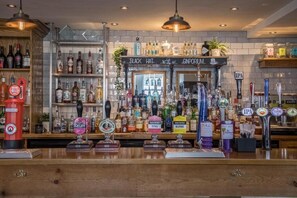 Eine Bar mit einer Auswahl an Spirituosenflaschen, mehreren Zapfhähnen für Bier und einer roten Telefonzelle.