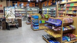 Un supermercado con varios pasillos repletos de productos como aperitivos, bebidas y artículos para el hogar.