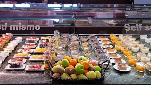 Mostrador de autoservicio con diversos pasteles, postres y frutas.
