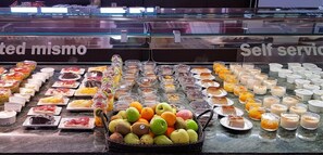 Mostrador de autoservicio con diversos pasteles, postres y frutas.