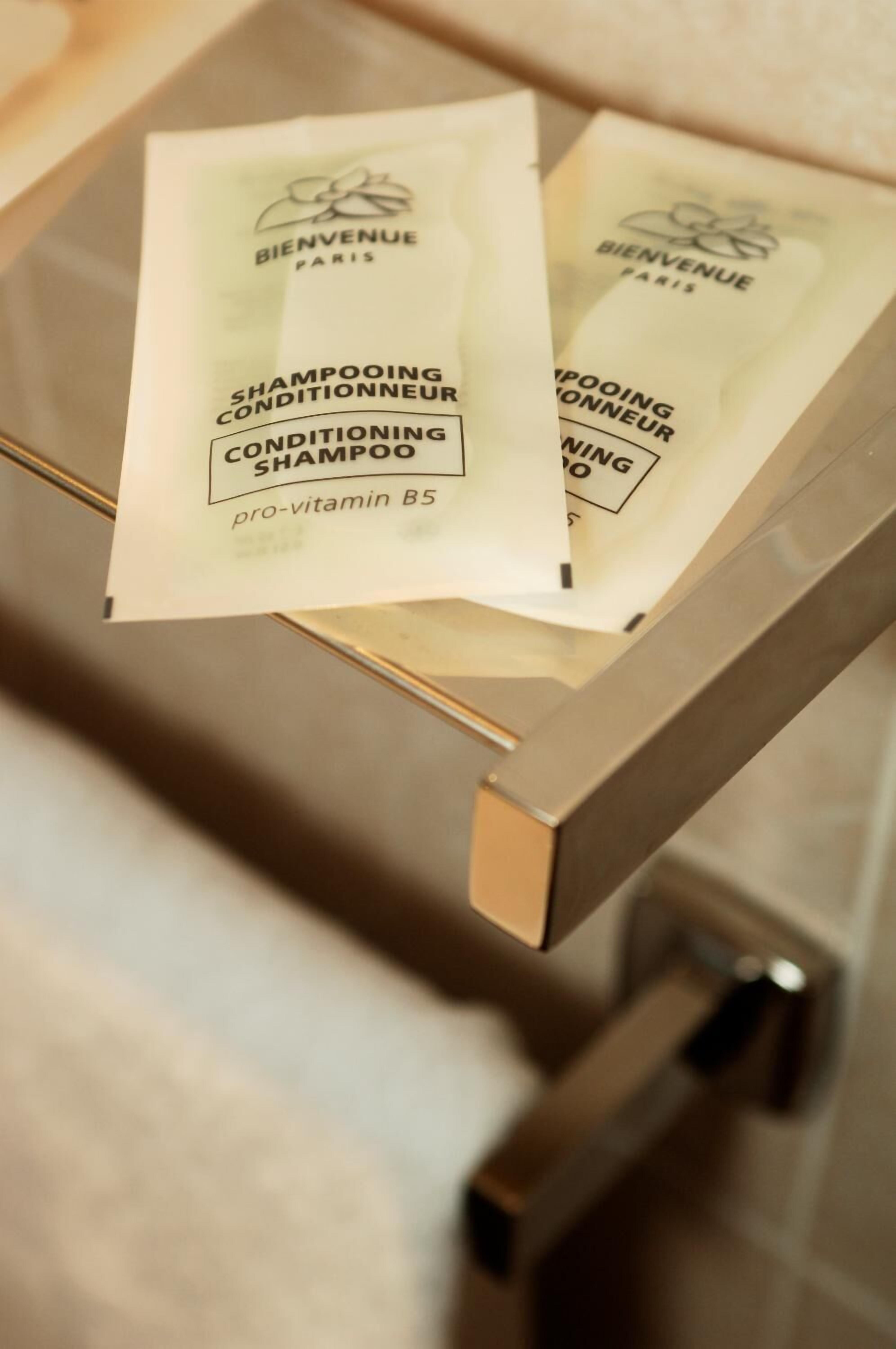 Two packets of 'Shampooing Conditionneur' with 'pro-vitamin B5' on a metallic surface.